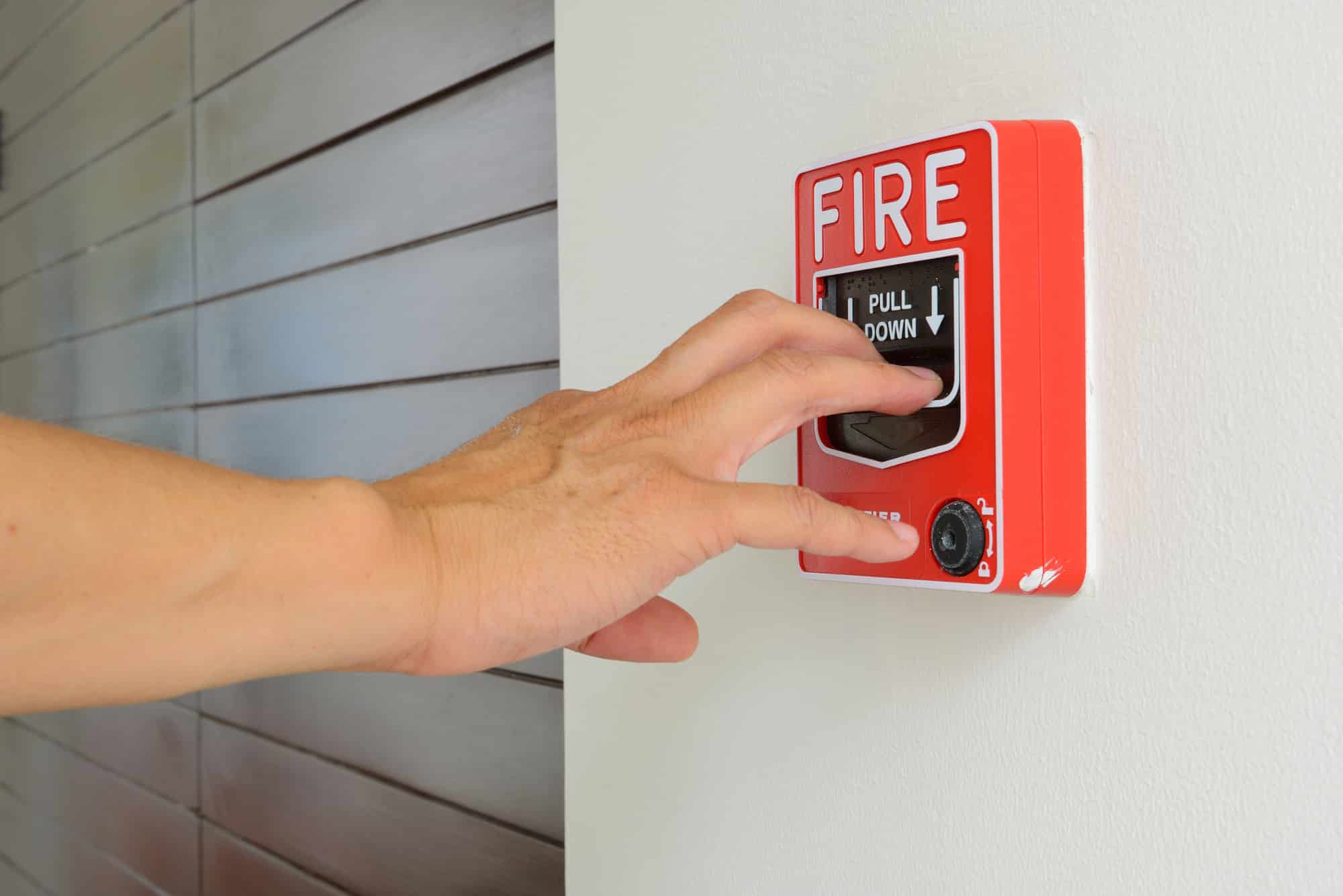 The hand of man is pulling fire alarm